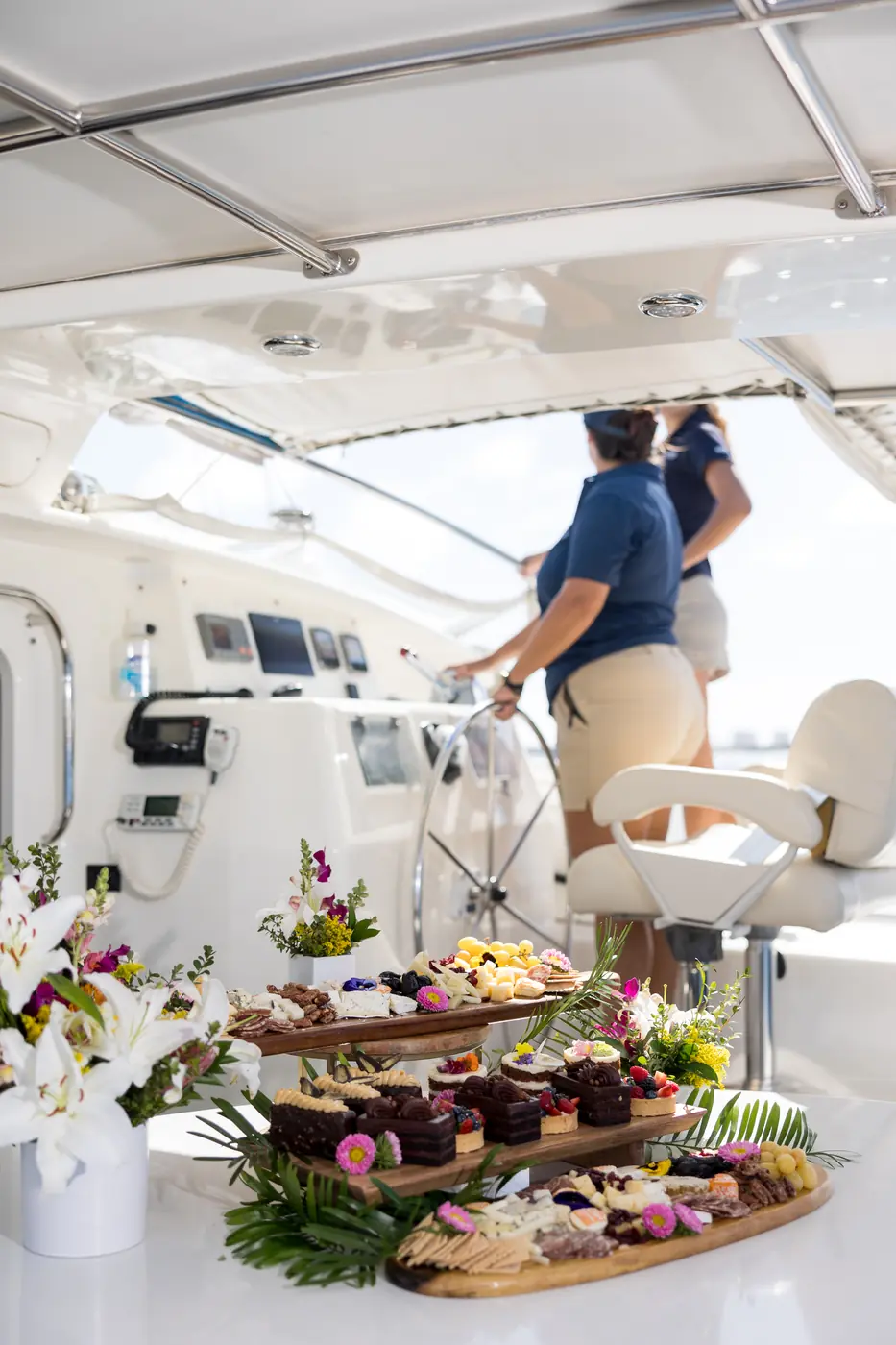 Tiered charcuterie spread on Malarky's aft cockpit with the captain at the helm