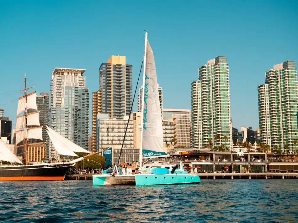Malarky's 47ft sailing catamaran under sail on San Diego Bay near the Star of India
