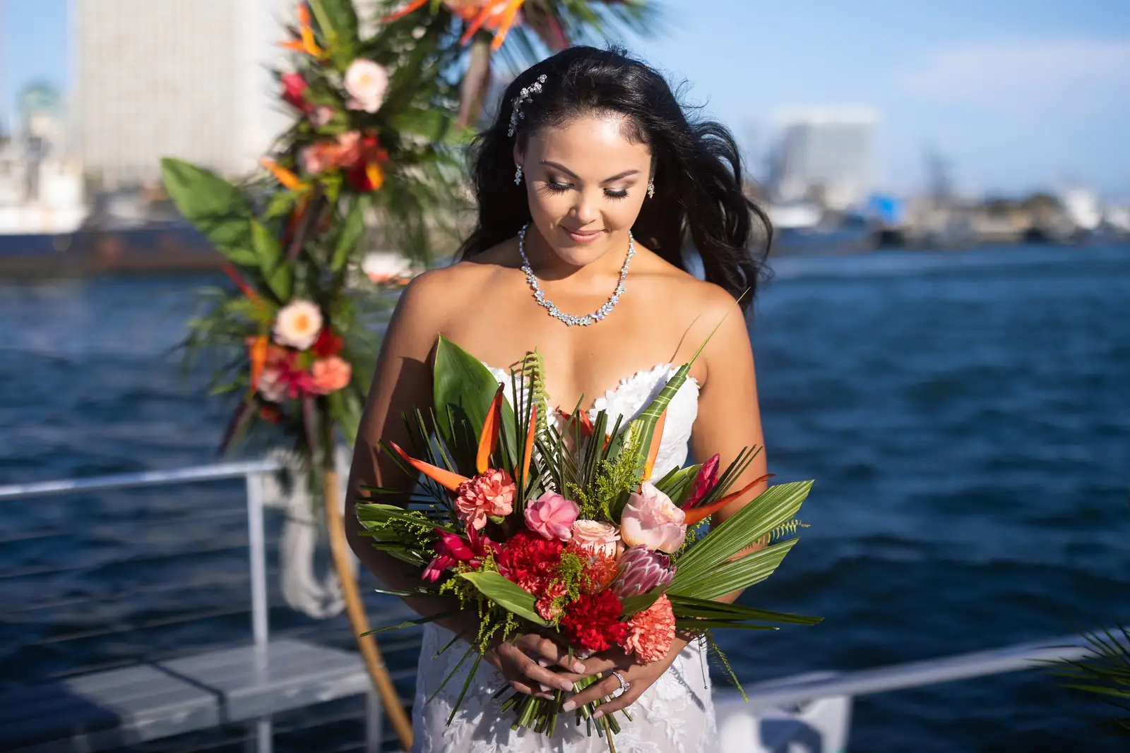 Bride with tropical bouquet at floral wedding arch aboard Malarky on San Diego Bay