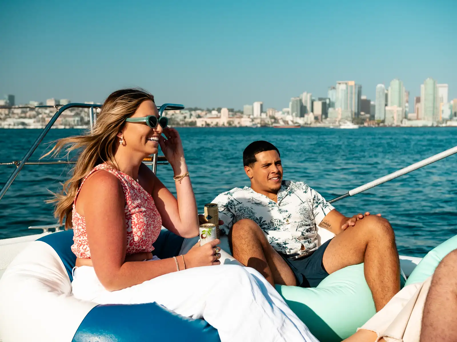 Couple lounging with BYOB drinks on Malarky's aft deck with San Diego skyline behind