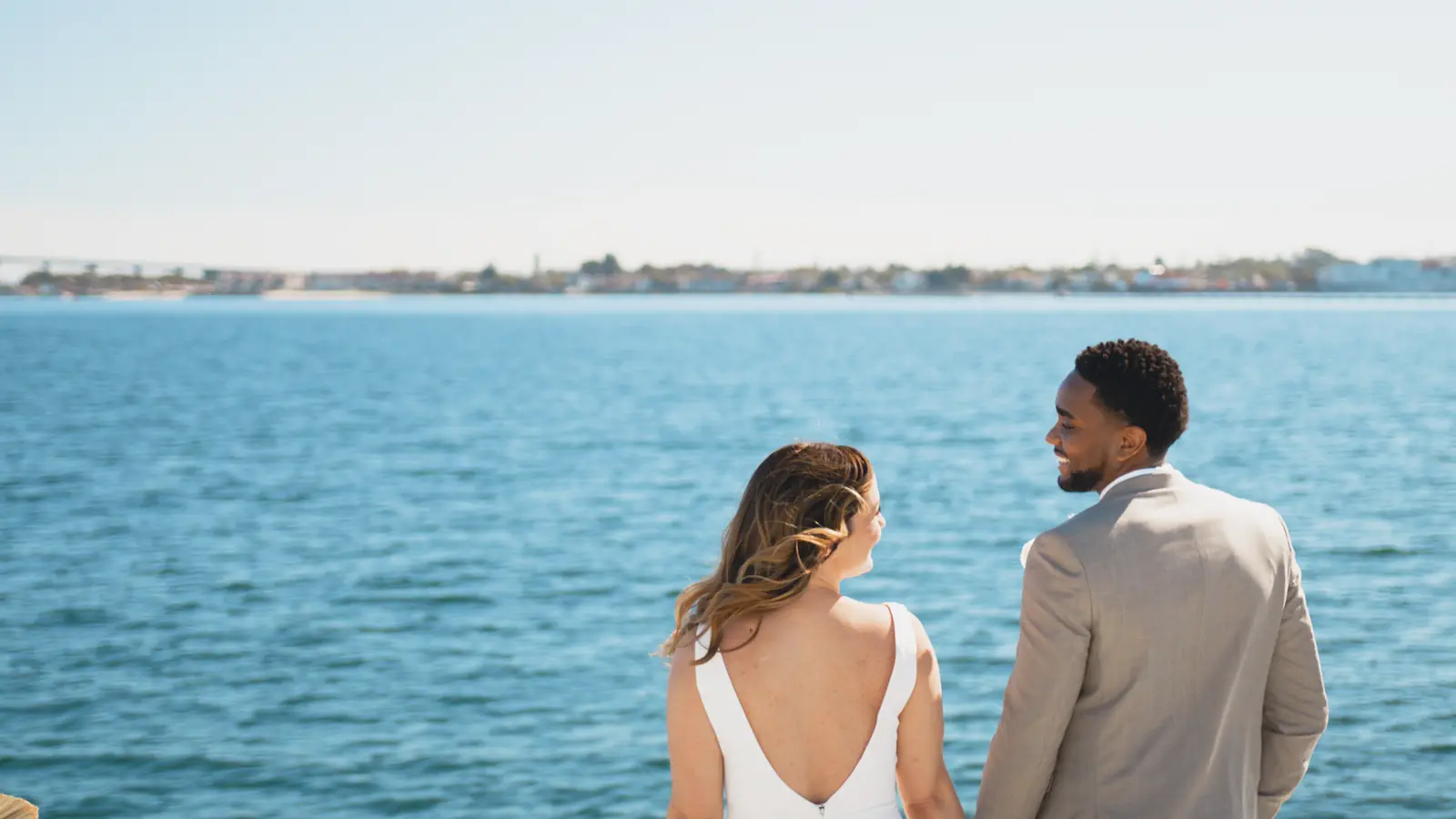 Wedding couple holding hands looking out over San Diego Bay aboard Malarky